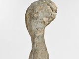 sculpture of a hand holding a rock on a white surface
