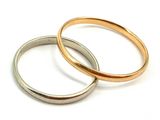 two gold and silver wedding rings on a white surface