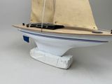 a small model sailboat on a stand on a white surface