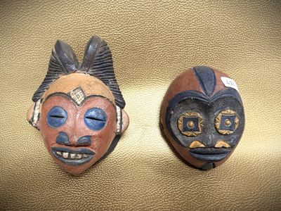 two wooden masks are sitting on a gold surface