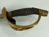 a close up of a gold and black sword on a white surface