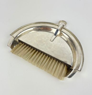 a close up of a brush with a metal handle on a white surface