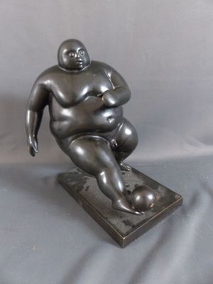 statue d'un homme corpulent assis sur une assiette, sur fond gris