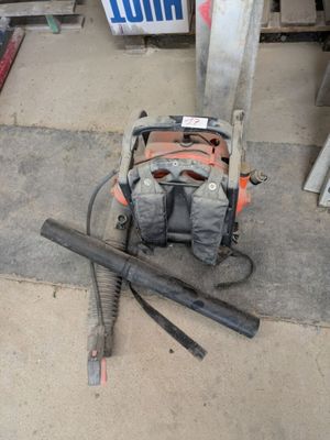 a bag and a saw on the ground next to a gas pump
