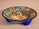 a blue bowl with a design on it sitting on a stand