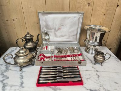 des couverts en argent posés sur une table à côté d'une théière en argent