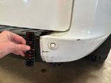 a person measuring the width of a car ' s bumper