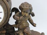 a statue of an angel sitting on a rock next to a clock