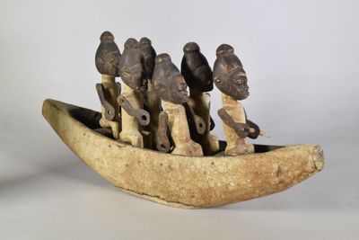 plusieurs figurines représentant des personnes dans un bateau en bois, posées sur une surface blanche