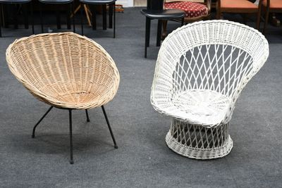 deux chaises en osier placées dans une pièce, avec d'autres chaises à l'arrière-plan