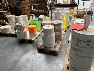 many rolls of paper sitting on pallets in a warehouse