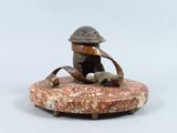 a small statue of a man sitting on a rock