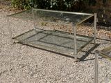 a glass coffee table and two chairs on the gravel