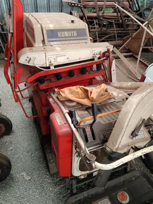 a red and white tractor parked next to a pile of junk