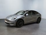 une Tesla Model Y argentée garée dans une pièce blanche