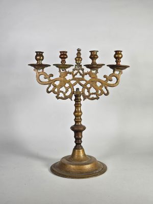 un candélabre ancien en laiton à quatre bougies, posé sur un socle