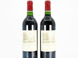 two bottles of red wine sitting next to each other on a white surface