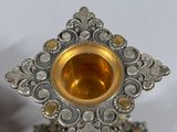 a silver and gold candle holder on a white surface