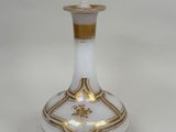 un vase blanc et doré posé sur une surface blanche
