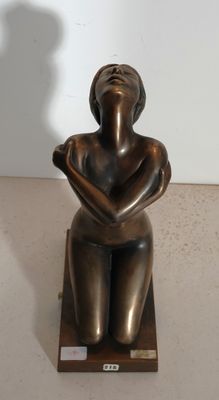 statue of a woman sitting on a wooden base with her hands on her knees