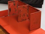 an old red metal box with two open doors on a wooden table