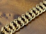 a close up of a gold chain bracelet on a wooden table
