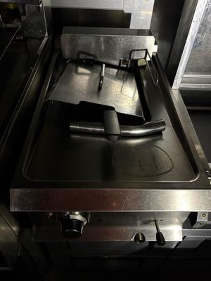 une plaque de cuisson noire sur laquelle se trouve un brûleur en métal