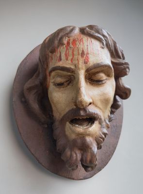 a statue of jesus with blood on his face on the wall