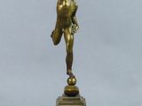 statue en bronze représentant un homme tenant une balle, posée sur un socle en bois