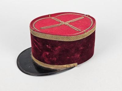 un chapeau haut-de-forme rouge orné d'un ruban doré sur fond blanc