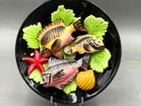 un saladier noir rempli de poisson et de légumes posé sur une table