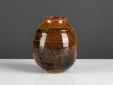 un vase marron posé sur une table blanche