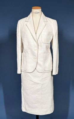 a white dress and jacket on a mannequin stand