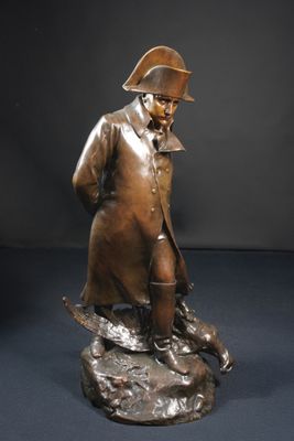 statue en bronze représentant un homme coiffé d'un chapeau et vêtu d'un manteau, assis sur un rocher