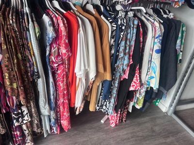 beaucoup de vêtements suspendus à une étagère dans une pièce