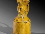 une image représentant un vase jaune sur lequel figure une tête d'homme
