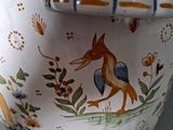 a vase with a lid that has a picture of a bird on it
