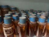 many bottles of liquid sitting on a shelf next to each other