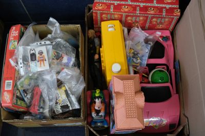 deux cartons remplis de jouets et d'autres objets posés par terre