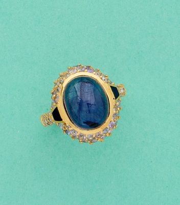 gros plan d'une bague avec une pierre bleue entourée de diamants
