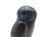 an image of a black owl statue sitting on top of a wooden base