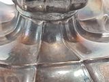 a close up of a silver vase with a bird on it