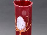 a red vase with a flower painted on it