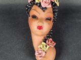 une tête de femme en argile, avec des fleurs dans les cheveux