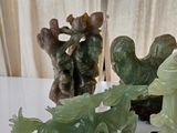 three jade figurines sitting on a white table