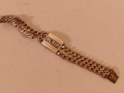 une photo d'un bracelet en argent sur lequel est accrochée une étiquette avec un nom