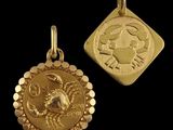 a close up of two gold zodiac charms on a black background