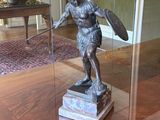 une statue représentant un homme tenant un bouclier, posée sur une table