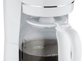La cafetière est blanche et est équipée d'une carafe en verre.