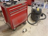 a garage with a red tool box and a vacuum in it